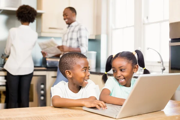 Siblings using laptop in kitchen — Stock Photo, Image