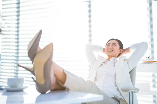 Avslappnad affärskvinna sitter med fötterna upp — Stockfoto
