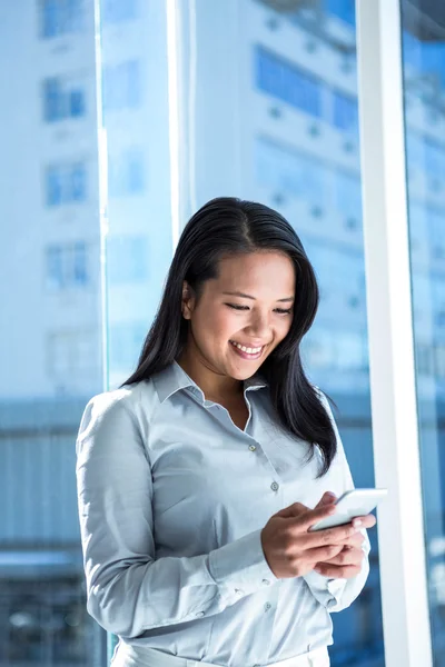 Femme d'affaires souriante utilisant un smartphone — Photo