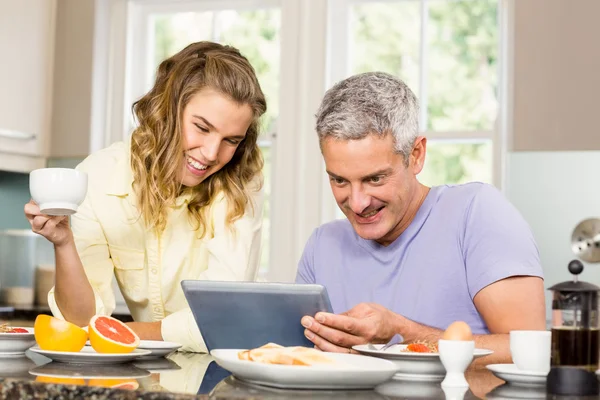 Casal usando tablet e tomando café da manhã — Fotografia de Stock