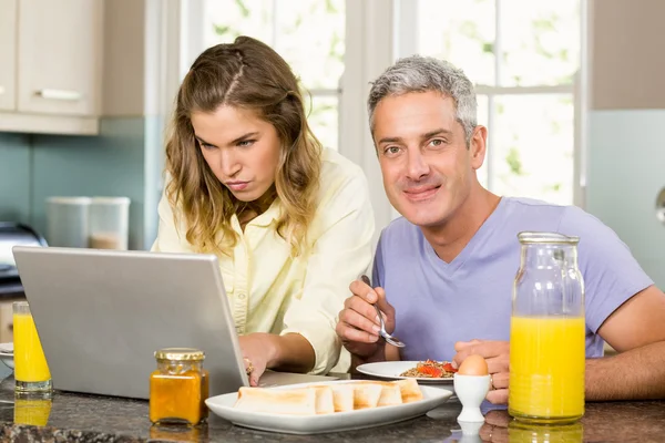 Couple using laptop and having breakfast — Stock Photo, Image