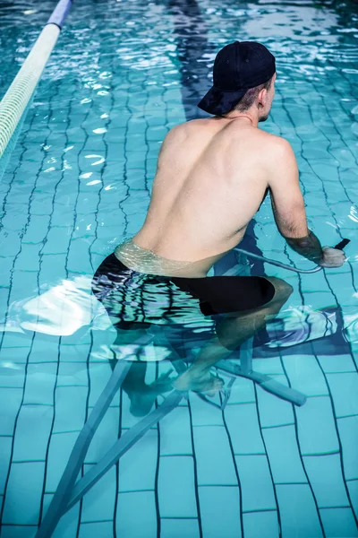 Fit man cycling in the pool — Stock Photo, Image