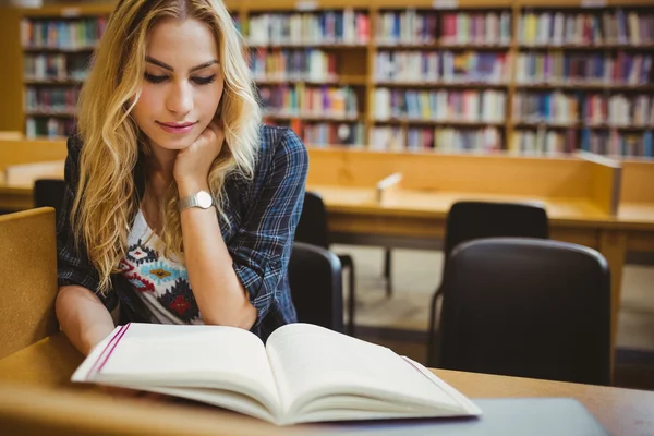 Estudiante sonriente leyendo libro en la mesa —  Fotos de Stock