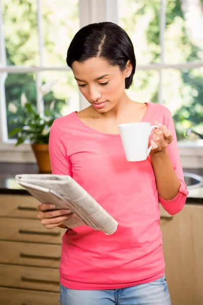 Morena segurando copo e jornal — Fotografia de Stock