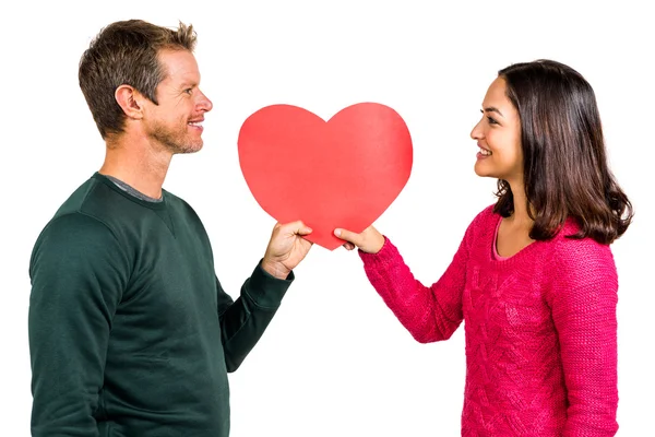 Couple souriant tenant forme de coeur rouge — Photo