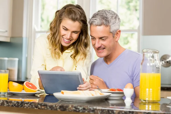 Paar benutzt Tablet und frühstückt — Stockfoto