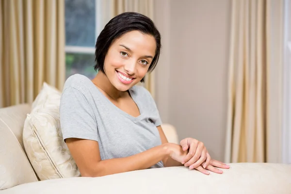 Bruna sorridente seduta sul divano — Foto Stock