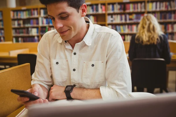 Smiling student using his smartphone — Stock Photo, Image