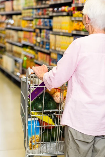 Vrouw duwt trolley in supermarkt — Stockfoto