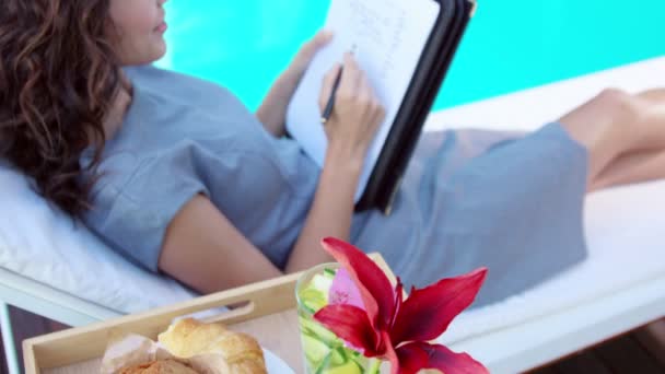 Pretty brunette taking notes on deckchair — Stock Video