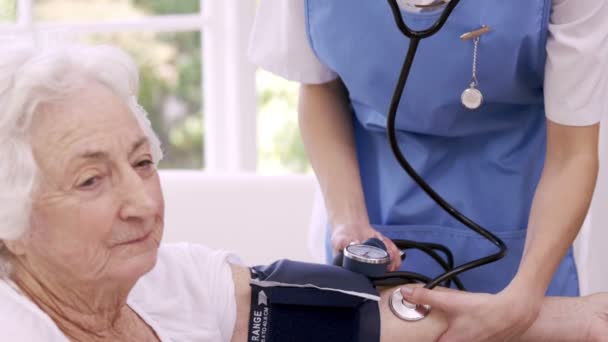 Infermiera controllando la pressione sanguinosa della donna anziana — Video Stock