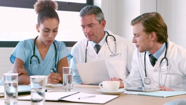 Equipo médico hablando juntos mientras buscan carpeta — Vídeo de stock