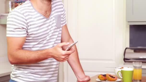 Homem usando seu smartphone na cozinha — Vídeo de Stock