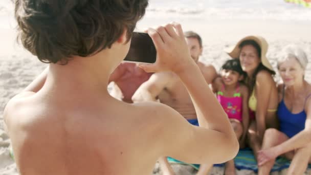 Милый мальчик фотографирует свою семью со смартфона — стоковое видео