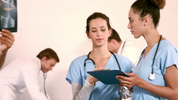 Медична команда розмовляє, коли медсестра дивиться рентгенівський знімок — стокове відео