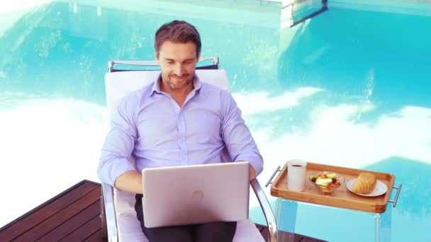 Bonito homem usando laptop na cadeira deck — Vídeo de Stock