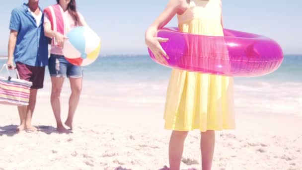 Niña jugando con su boya en la playa con sus padres — Vídeo de stock