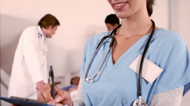 Nurse writing on her clipboard — Stock Video