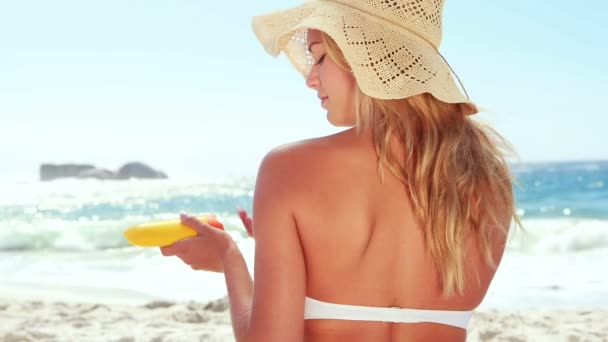 Belle blonde avec chapeau mettant crème solaire — Video