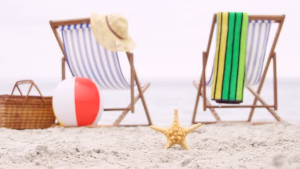 Палубные стулья и морская звезда на песке — стоковое видео