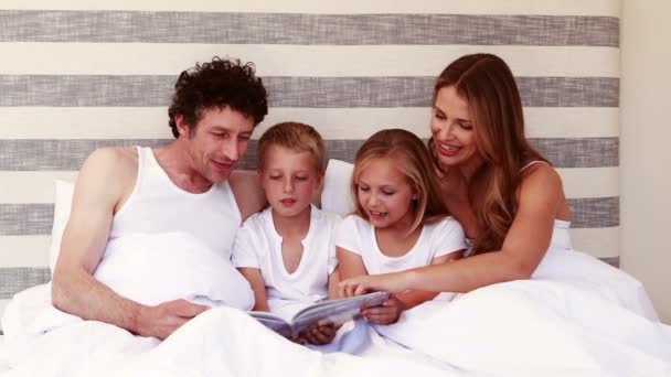 Glückliche Familie liest Buch auf dem Bett — Stockvideo