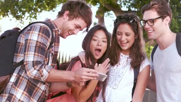 Друзья-хипстеры смеются, глядя на смартфон — стоковое видео