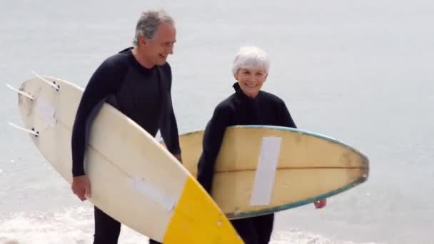 Pareja jubilada caminando con tablas de surf — Vídeo de stock