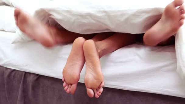 Paar Füße ragten unter Bettdecke hervor — Stockvideo