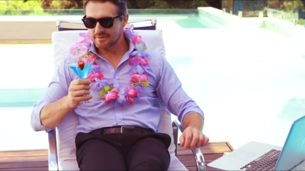 Расслабленный мужчина пьет коктейль и пользуется ноутбуком — стоковое видео