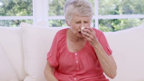 年配の女性がソファにくしゃみ — ストック動画