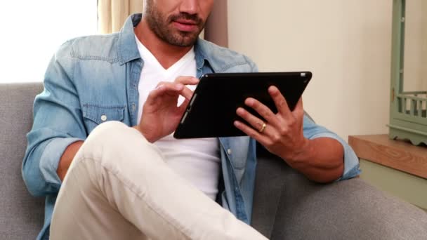 Bonito homem no sofá usando tablet — Vídeo de Stock