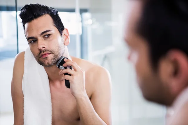 Handsome man shaving in the mirror — Stock Photo, Image