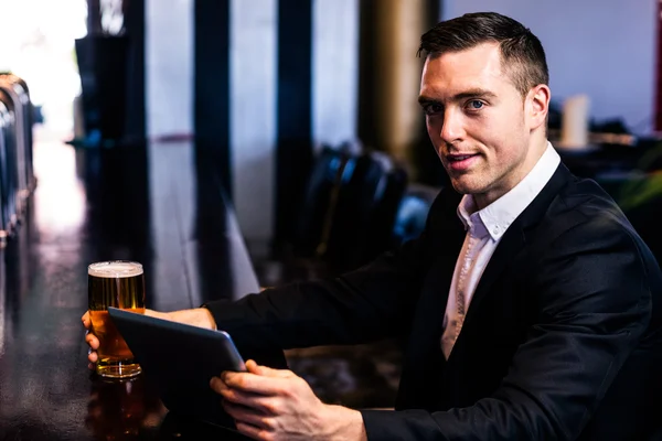 Businessman using tablet having beer — Stock Photo, Image