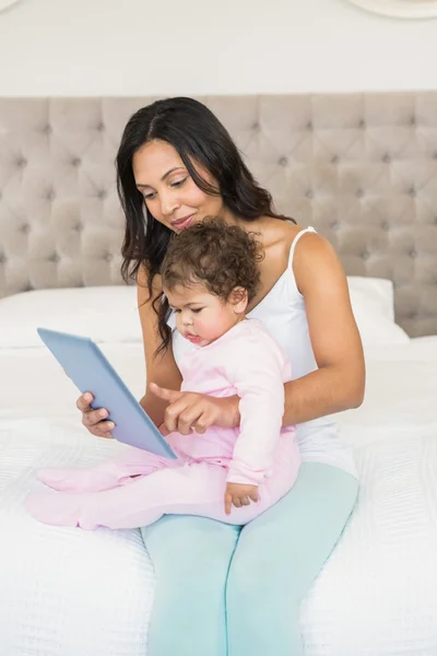 Morena segurando bebê e usando tablet — Fotografia de Stock