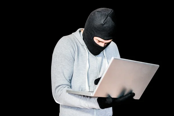 Focused thief with hood typing on laptop — Stock Photo, Image