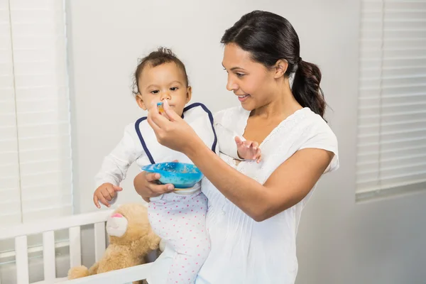 Lachende brunette voeding baby — Stockfoto