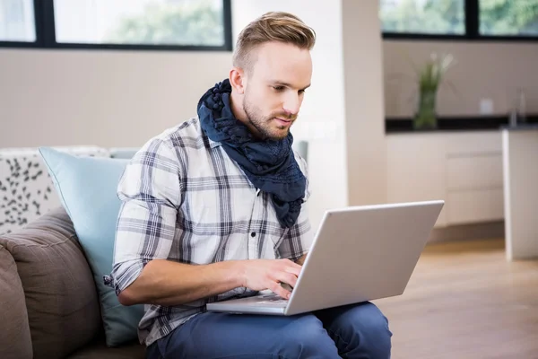 Knappe man met behulp van de laptop op de Bank — Stockfoto