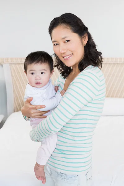 Smiling mother carrying baby daughter — Stock Photo, Image