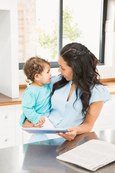 Brünette hält Baby und benutzt Tablette — Stockfoto