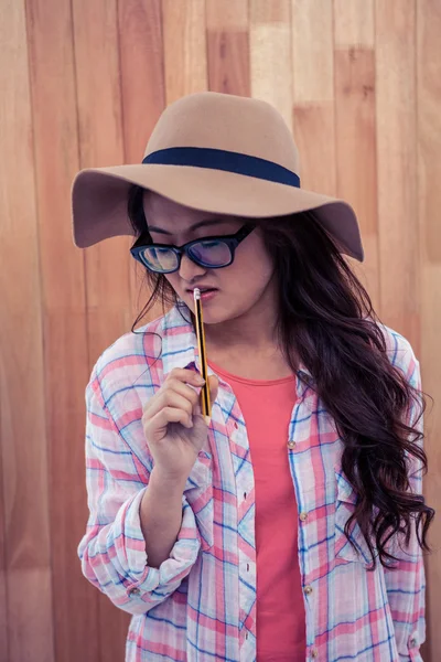 Aziatische vrouw met hoed bedrijf potlood — Stockfoto