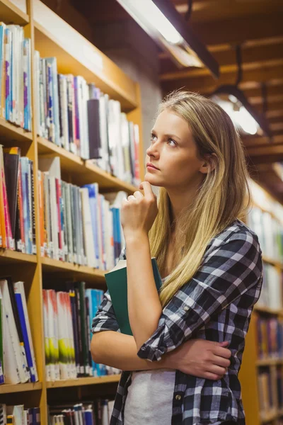 Thoughtful student looking at bookshelf — Stok fotoğraf