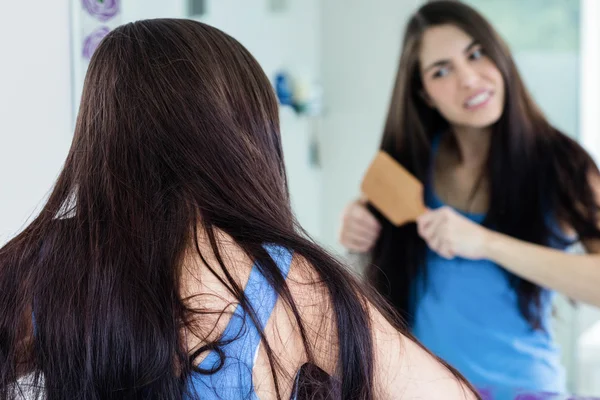 Unsmiling brunette combing — Stock Photo, Image