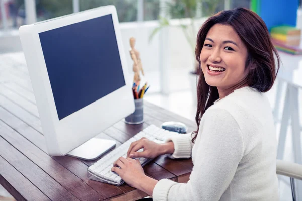 Asian woman on computer looking back — Stock Photo, Image