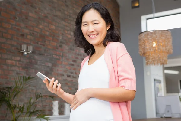 Těhotná žena držící smartphone — Stock fotografie