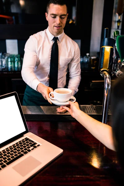 Barman dando café al cliente con portátil — Foto de Stock