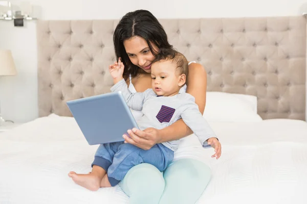 Morena segurando bebê e usando tablet — Fotografia de Stock