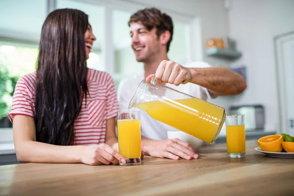 Hombre vertiendo jugo de naranja en el vaso — Foto de Stock