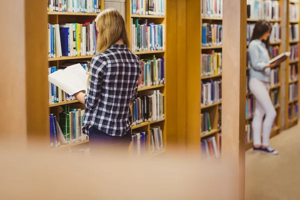 Students reading next to bookshelf — 스톡 사진