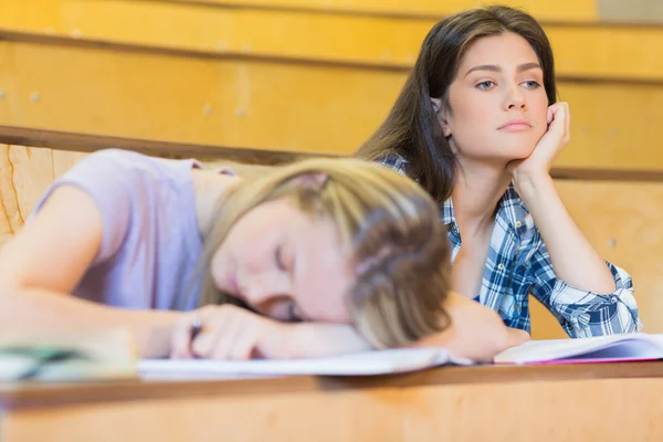 Estudiante aburrido escuchando mientras duerme compañero de clase — Foto de Stock