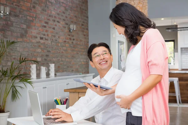 Mulher grávida mostrando tablet para marido — Fotografia de Stock